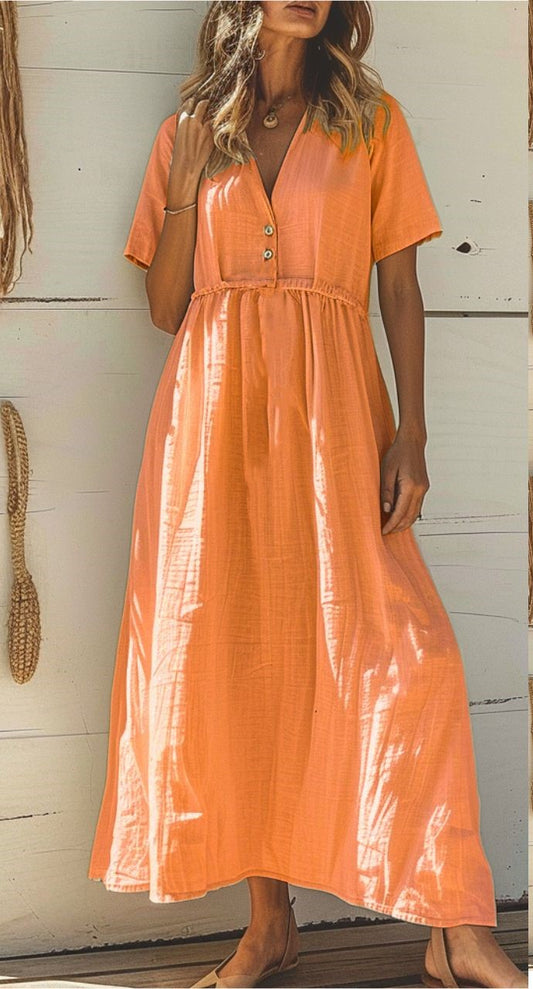 A woman wearing an orange maxi dress with short sleeves, a V-neckline, and button-down front.